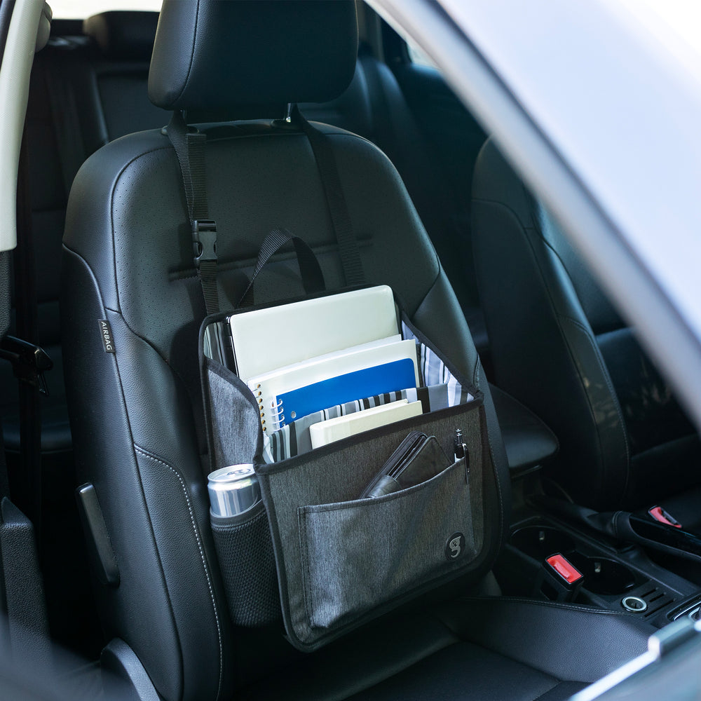 Grey fabric caddy organizer attached to passenger seat headrest with laptop, notebooks, wallet and canned drink geckobrands