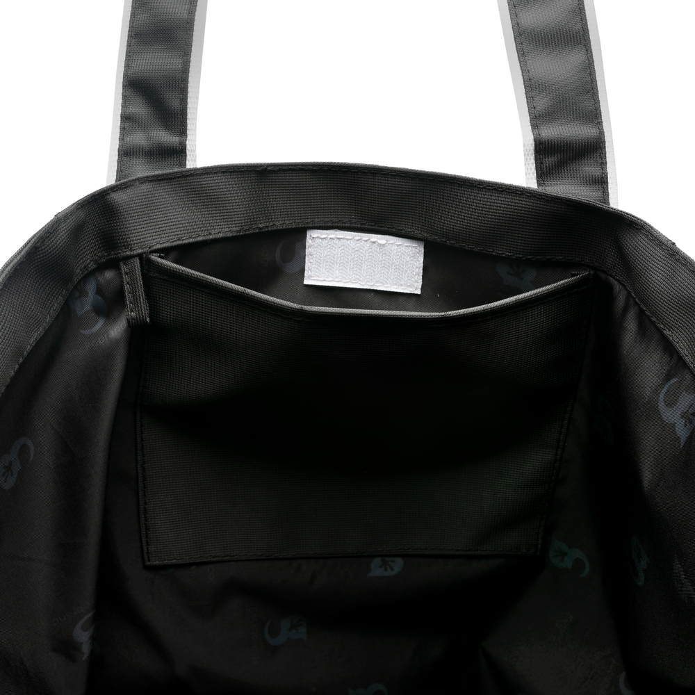Close-up of a beach tote bag with a visible brand label on a white background