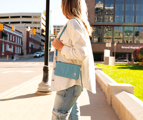 Person holding a blue crossbody bag on a city street