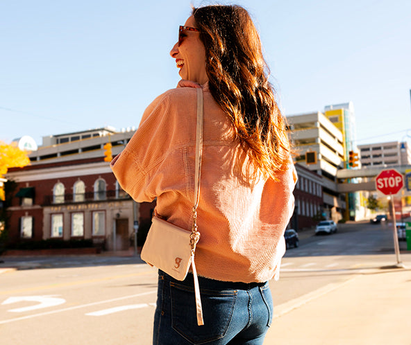 Woman walking on a city street with buildings and traffic lights in the background