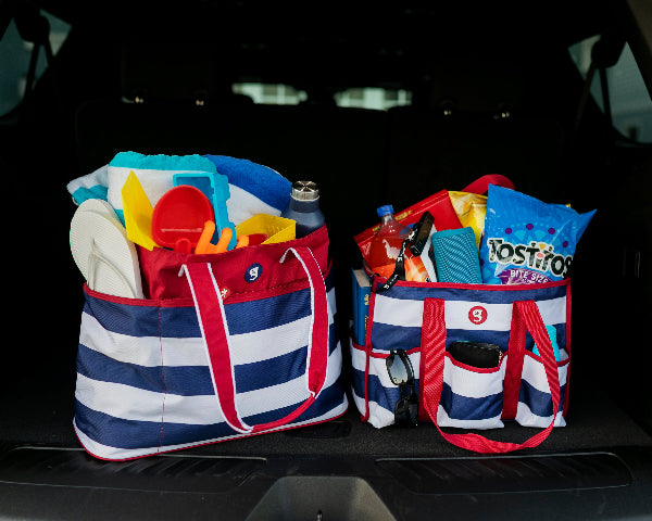 Two striped bags filled with beach items on a car trunk.