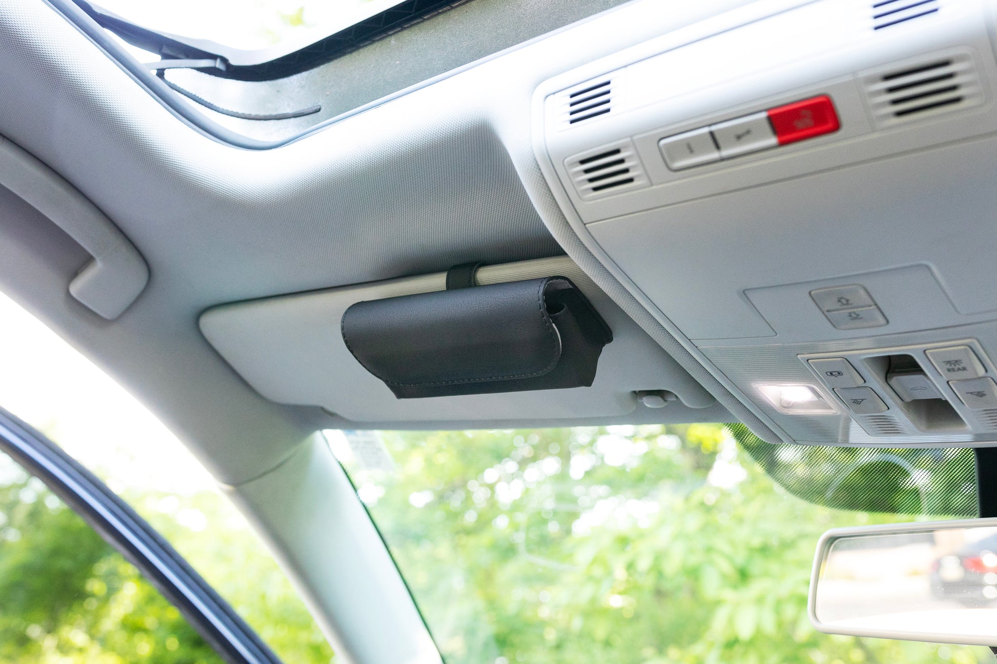 Magnetic black faux leather sunglasses case attached to a car's visor geckobrands