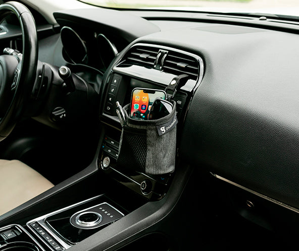 Grey fabric small bin hooked into car's air vent, storing phone and sunglasses, with pens in front mesh pocket. geckobrands