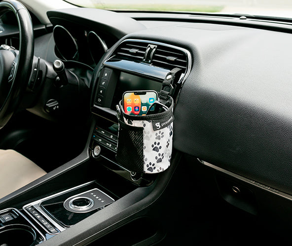 Paw printed fabric small bin hooked into car's air vent, storing phone and sunglasses, with pens in the front mesh pocket.