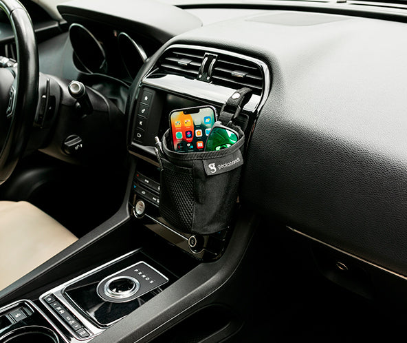 Grey fabric small bin hooked into car's air vent, storing phone and sunglasses, with pens in front mesh pocket. geckobrands