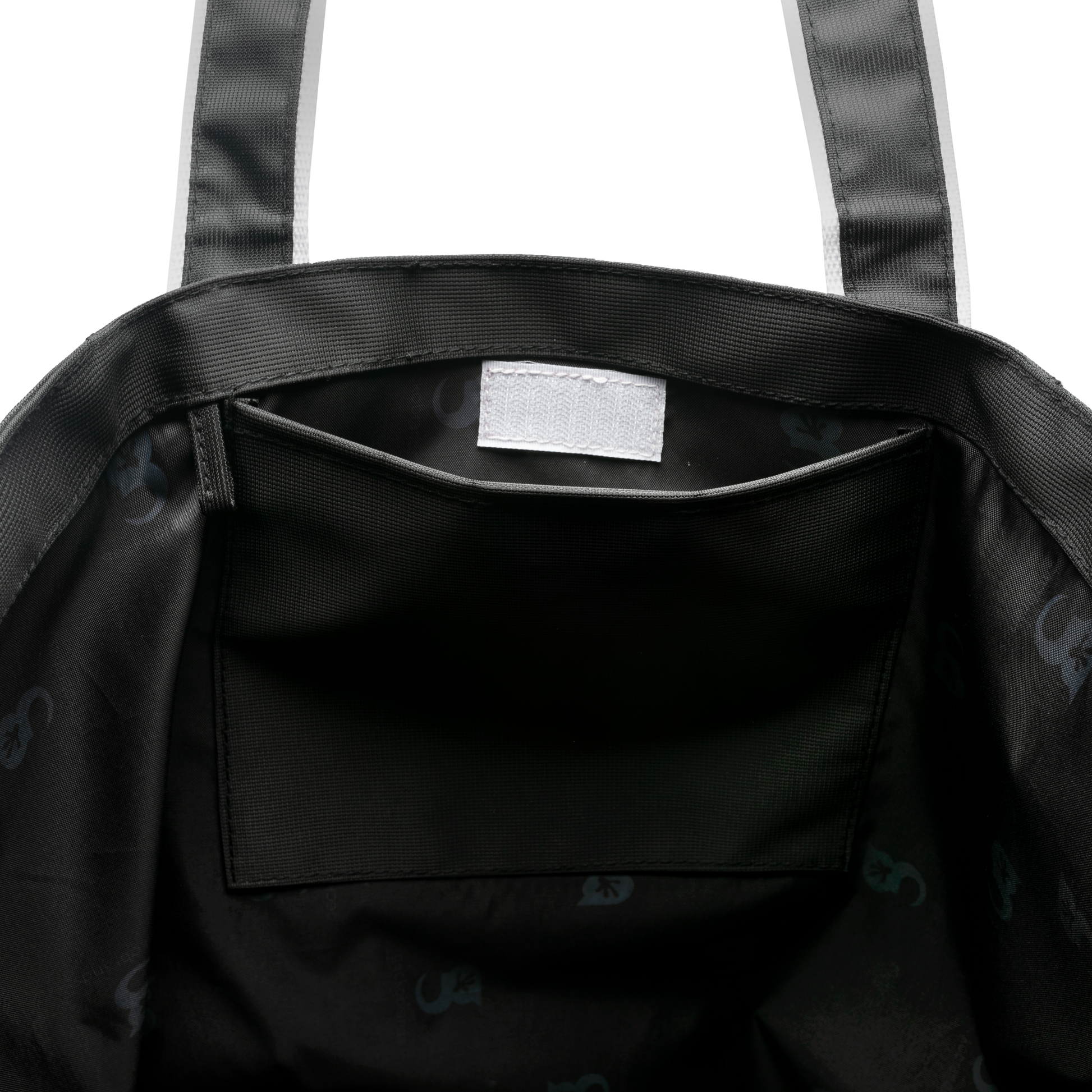 Close-up of a beach tote bag with a visible brand label on a white background