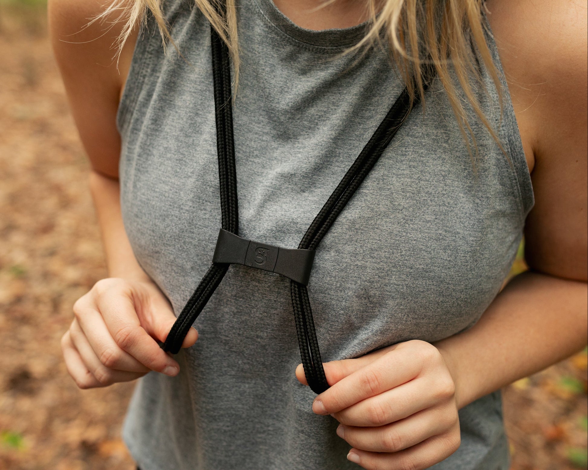 GDB-DSBP14_Person wearing a gray tank top with black suspenders against a blurred natural background