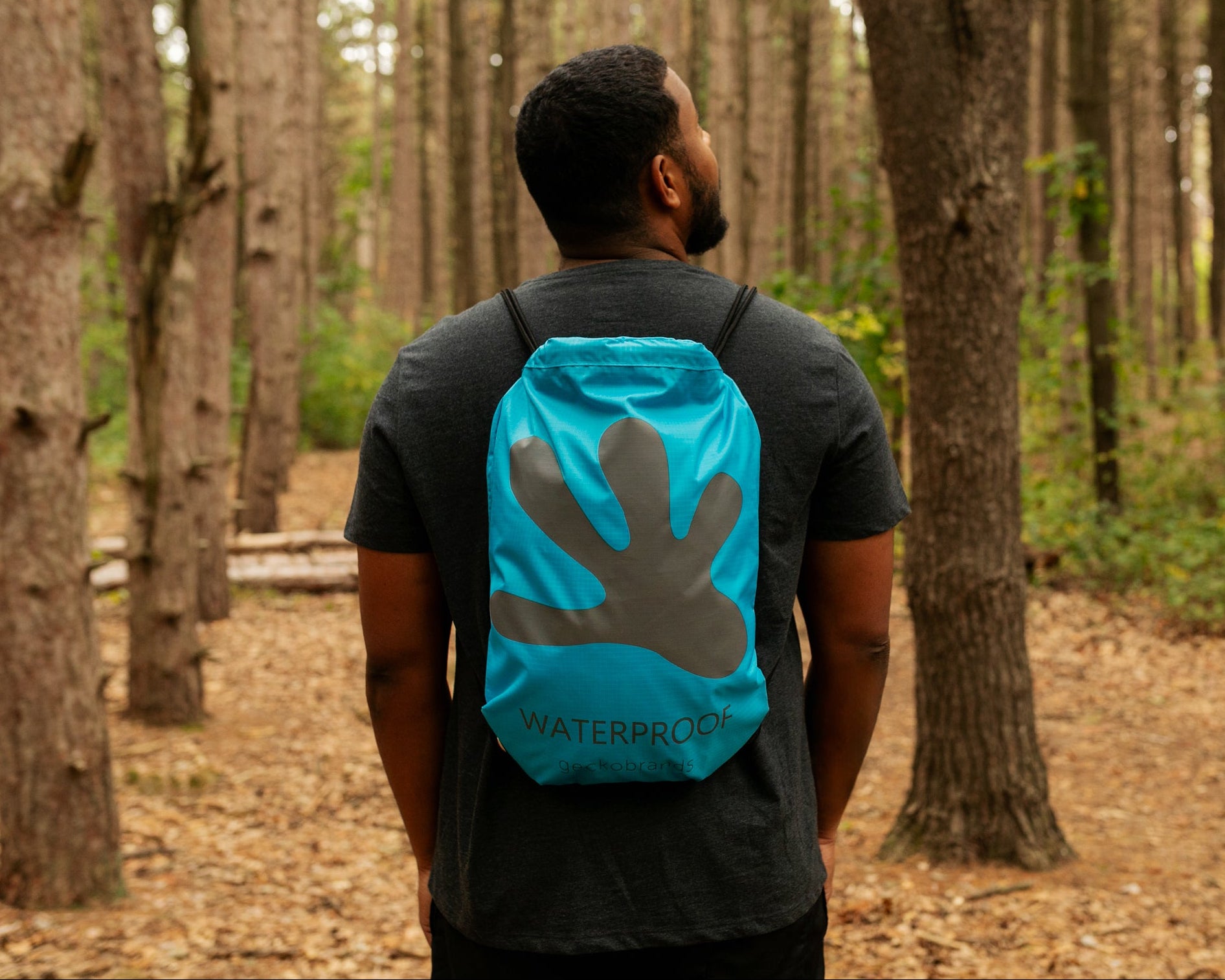 GWP-15055BB
Person wearing a blue backpack with a handprint design in a forest