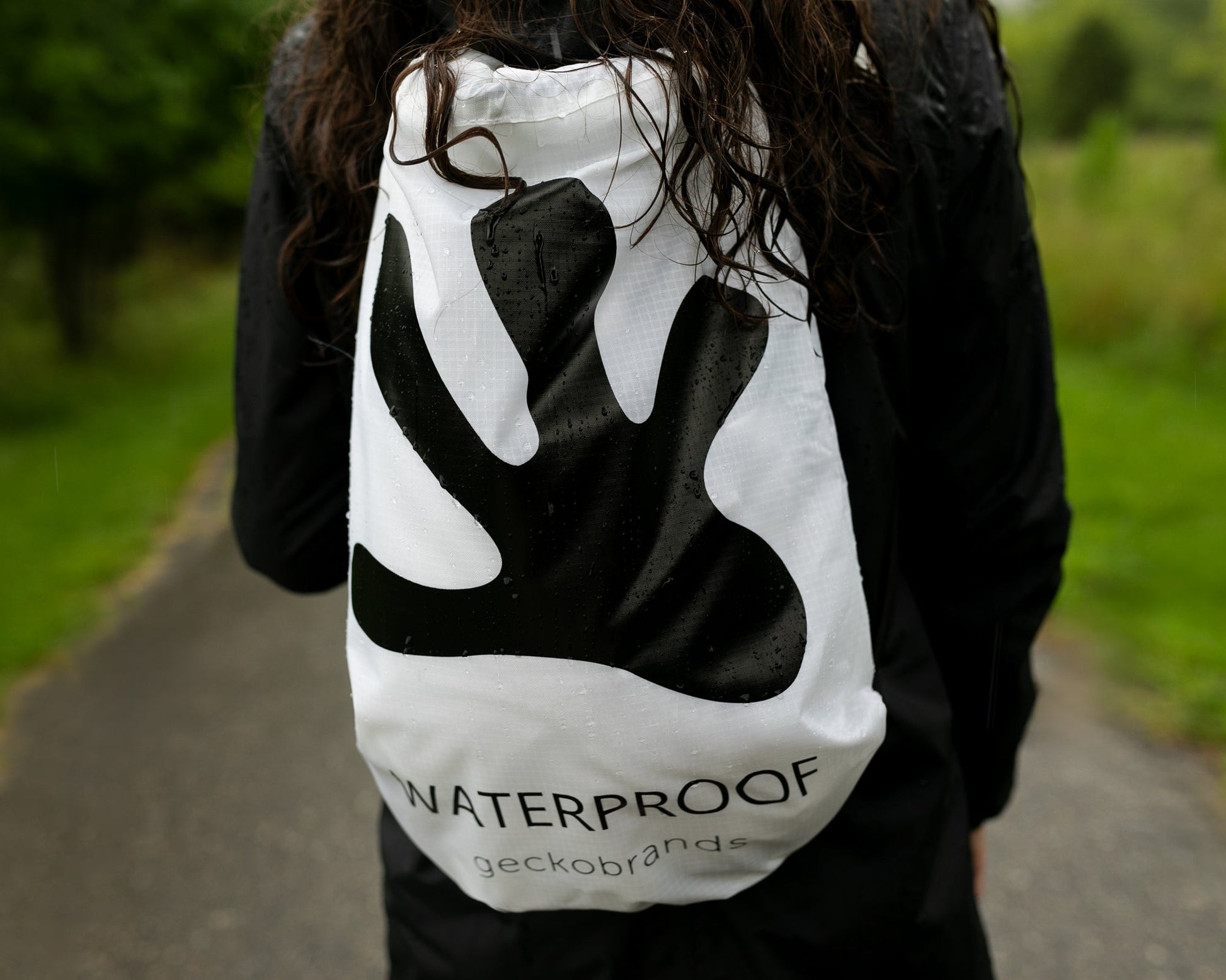 GWP-49000WB
Person wearing a white drawstring bag with black logo and text, outdoors on a path.