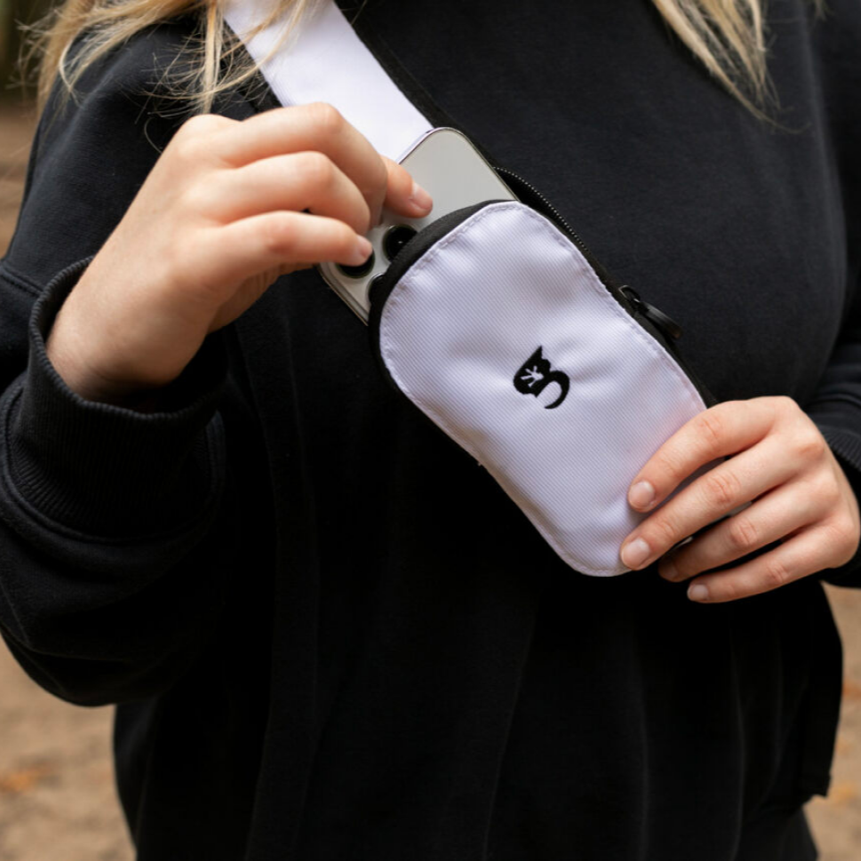 Person holding a white waist bag with a black cat logo.